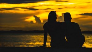 couple sitting on beach at sunrise