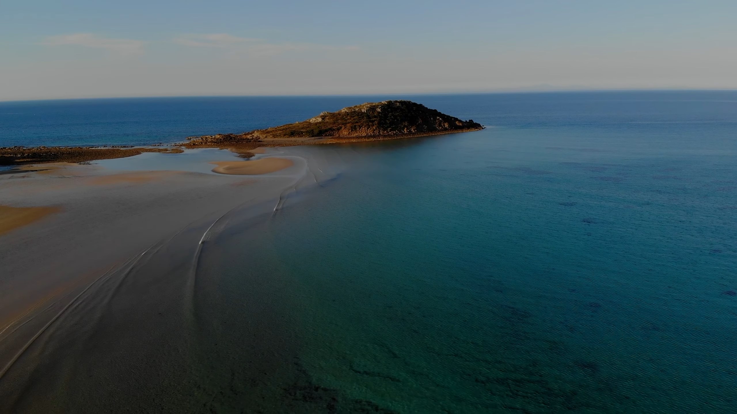 An arial pic from a drone of a beach with an island in the distance